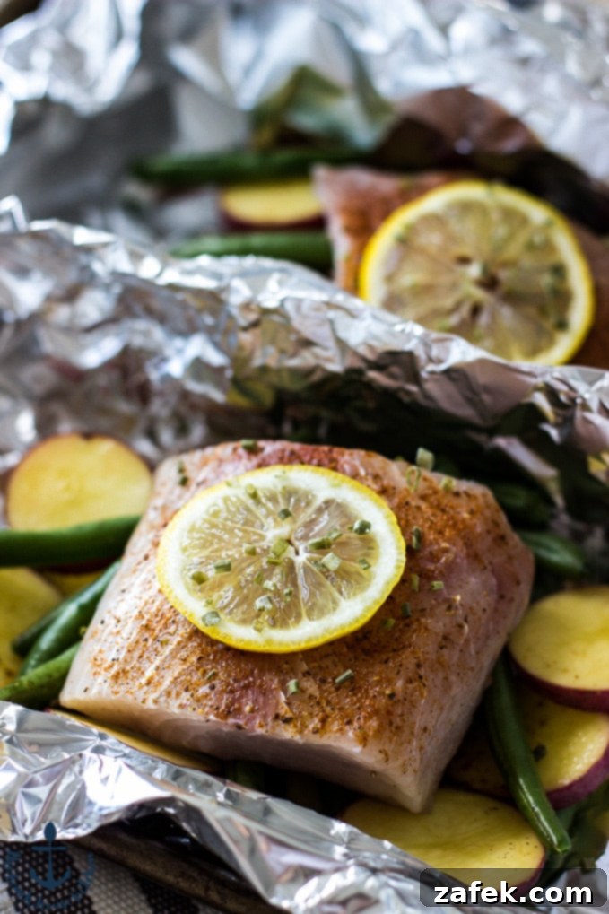 Savory Grilled Mahi Mahi and Veggie Foil Bundles 7 Opened Foil Packet Revealing Cooked Mahi Mahi with Lemon and Chives