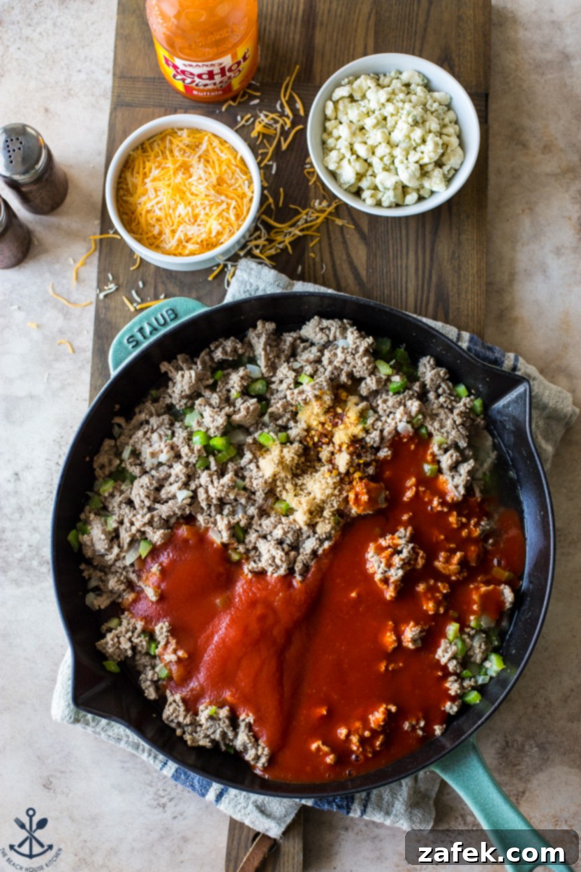 Spicy Buffalo Sloppy Joes 6 Overhead photo of a skillet filled with cooked turkey meat, rich tomato sauce, and softened vegetables, simmering together.