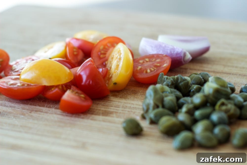 Close-up of fresh heirloom grape tomatoes, shallots, and capers – key ingredients for the vibrant sauce.