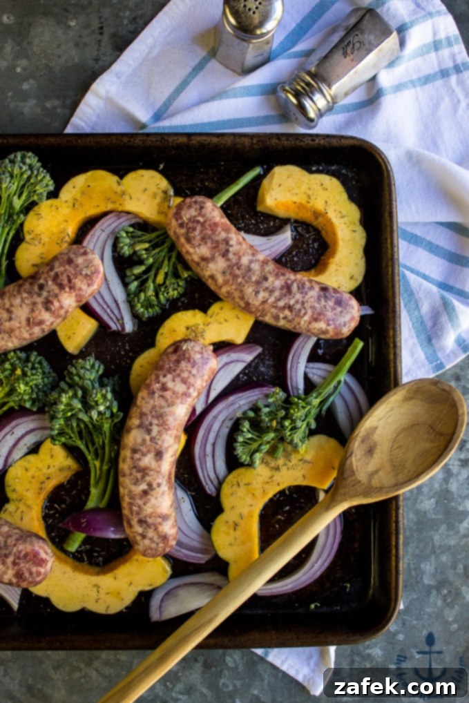 One-Pan Sausage & Acorn Squash Harvest 3 Close-up of roasted sausage and acorn squash on a sheet pan