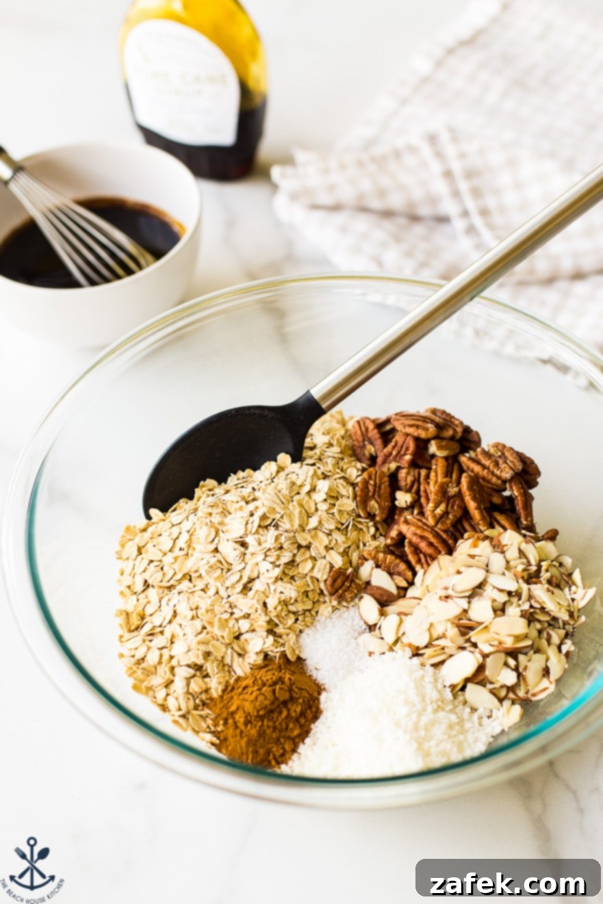 Ingredients for maple cinnamon granola in a glass bowl with a spoon