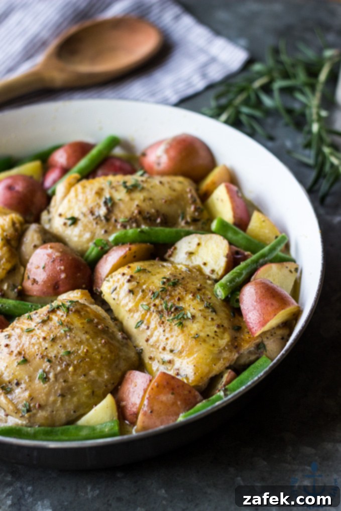 One Skillet Mustard Chicken with golden brown chicken, creamy sauce, red potatoes, and green beans in a rustic skillet