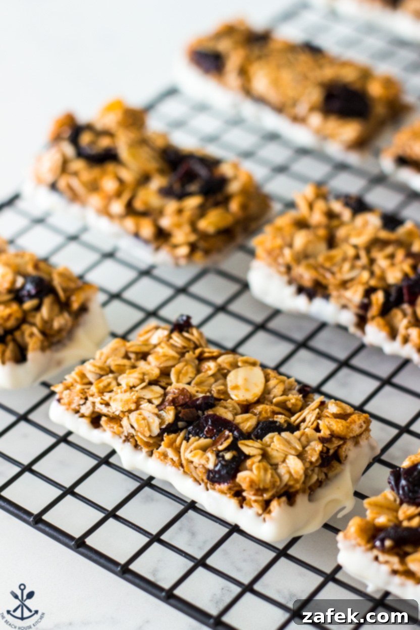 Up close photo of freshly dipped Chewy White Chocolate Dipped Blueberry Granola Bars cooling on a wire rack