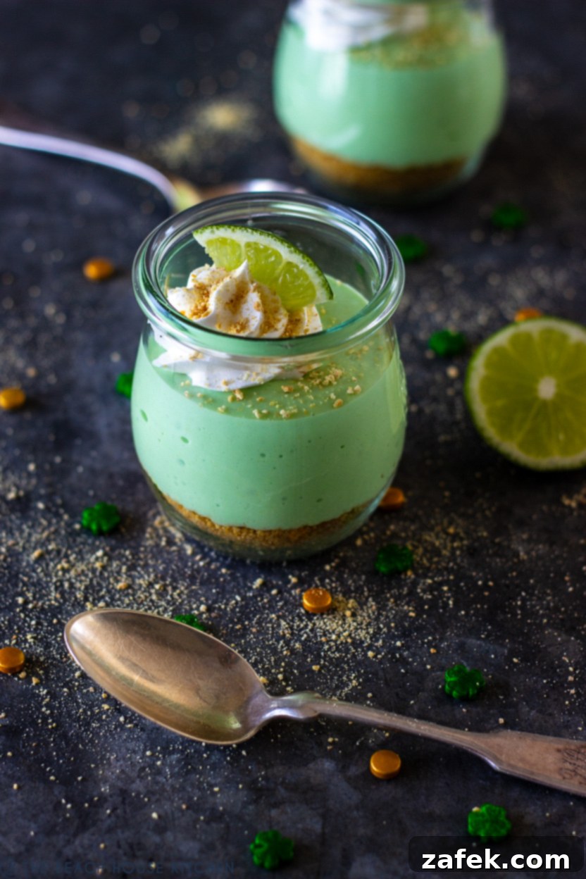 A close-up of a Mini No Bake Key Lime Pie Cheesecake in a jar, topped with fluffy whipped cream and a fresh lime slice.