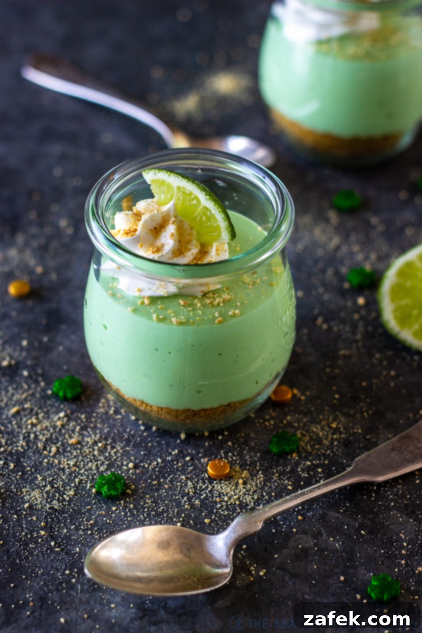 A close-up, tempting view of a Mini No Bake Key Lime Pie Cheesecake, showcasing its creamy texture, whipped cream, and lime garnish.