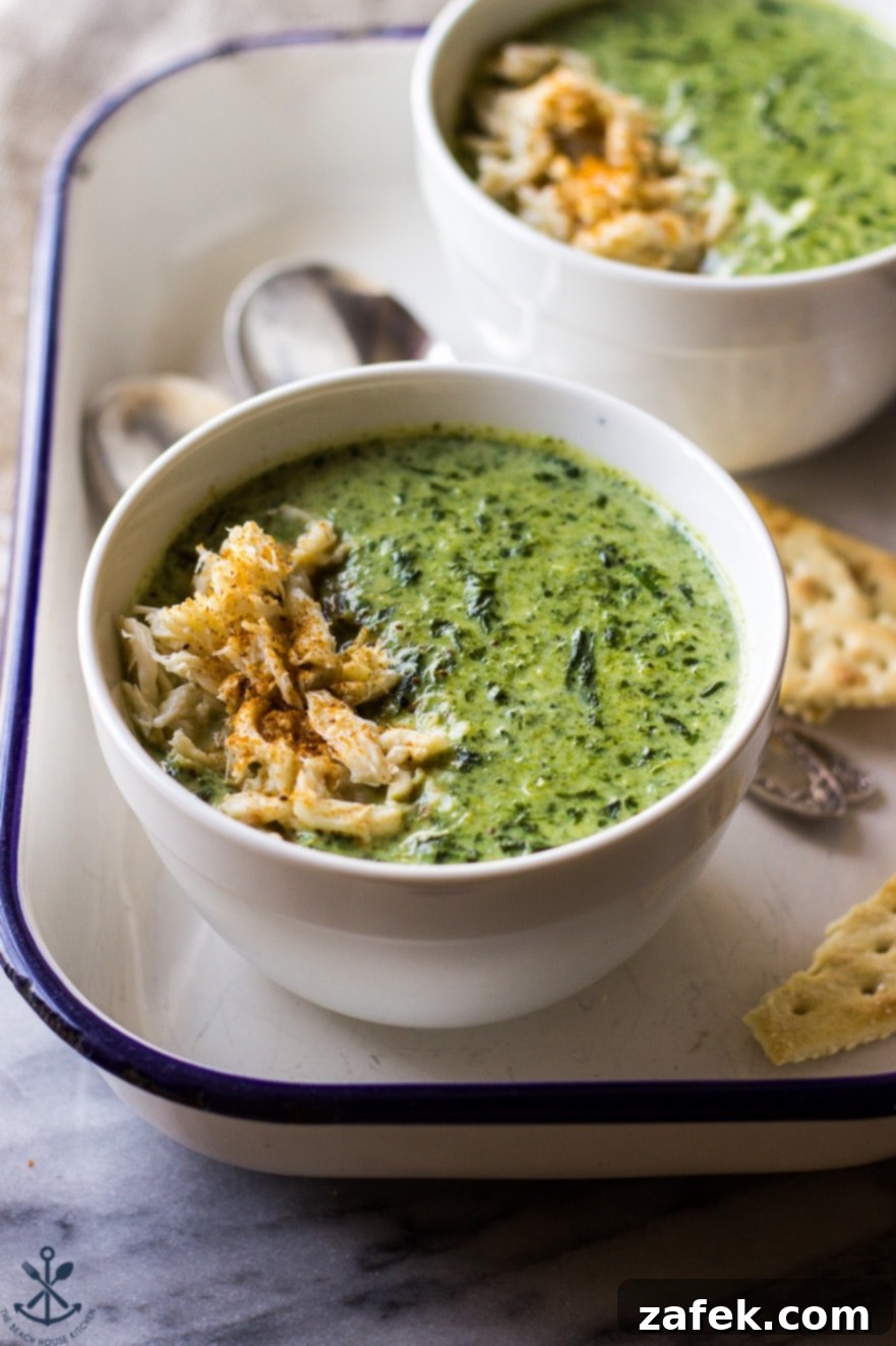 Velvety Crab and Spinach Bisque 3 Creamy Spinach Soup with Crabmeat in white bowls in an enamel tray with spoons and crackers