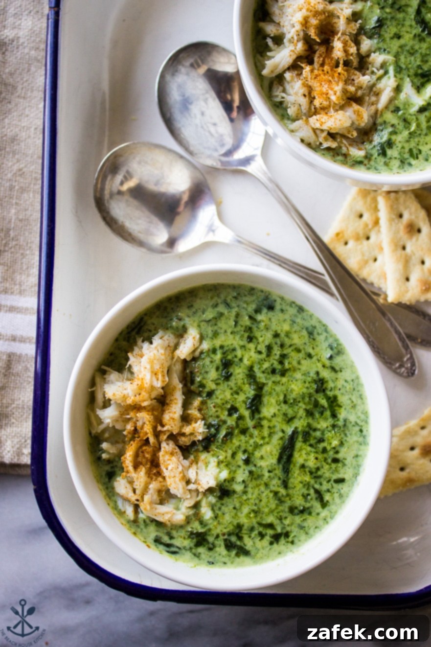 Velvety Crab and Spinach Bisque 4 Overhead photo of Creamy Spinach Soup with Crabmeat in a white bowl with two spoons