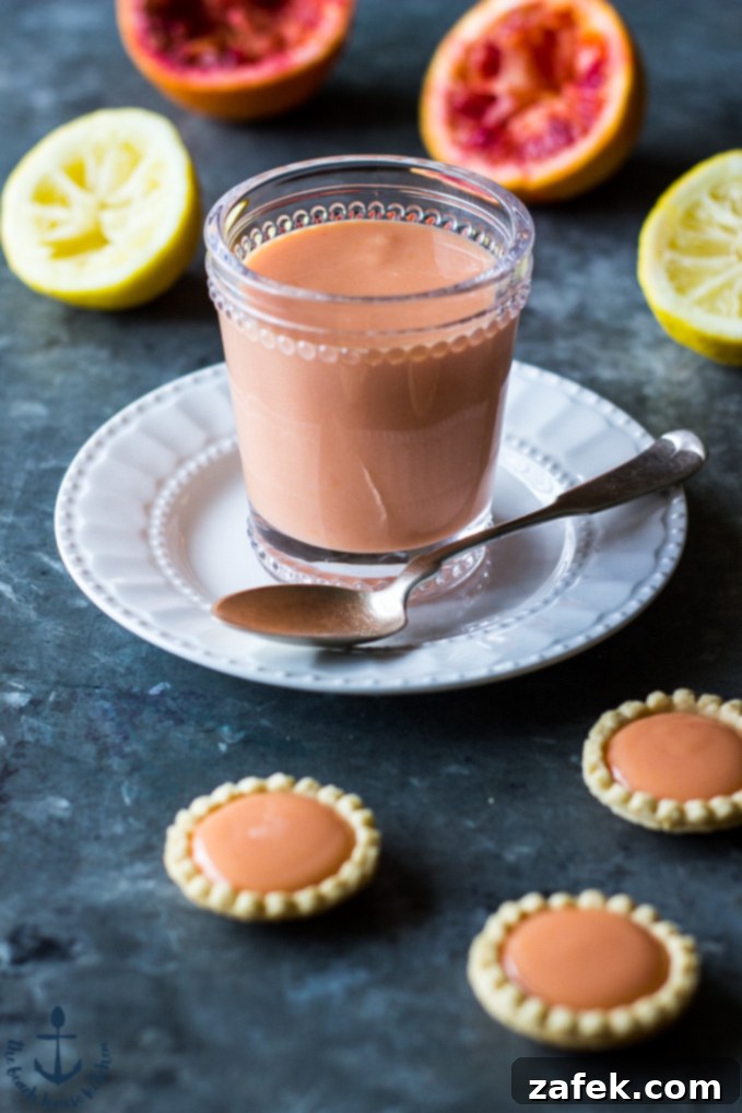 Sun-Kissed Ruby Curd 2 Beautiful Blood Orange Curd in a clear glass jar, garnished with a fresh blood orange slice and mint, ready to be served