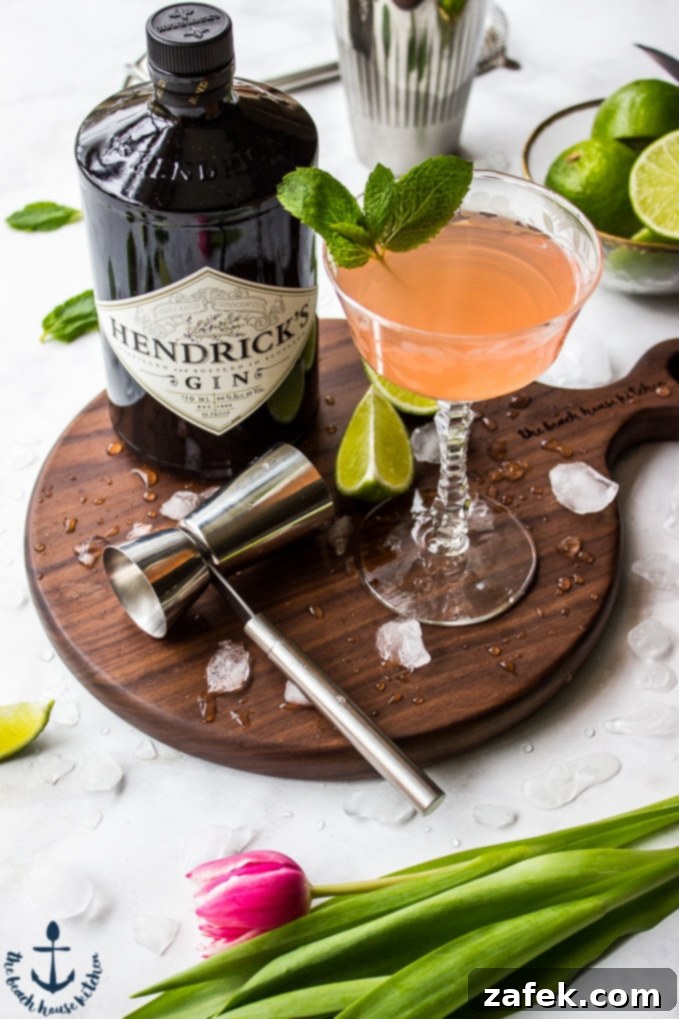Scarlet Zest Gimlet 3 Close-up view of a Ruby Red Gimlet cocktail with ice, mint, and a slice of grapefruit