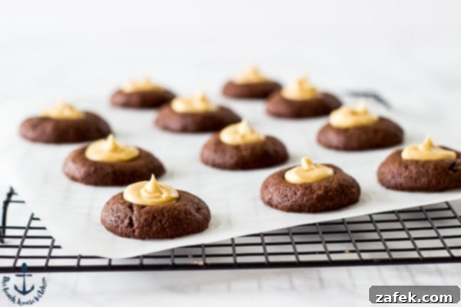 An overhead view of a tray of freshly baked Chocolate Peanut Butter Thumbprint Cookies, showcasing their uniform size and perfect indentations.