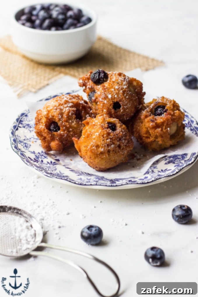 Plate of freshly fried blueberry fritters, lightly dusted with confectioner's sugar