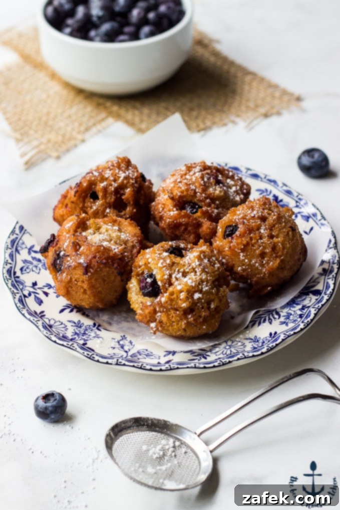 Arrangement of blueberry fritters with fresh blueberries and a sprinkling of powdered sugar
