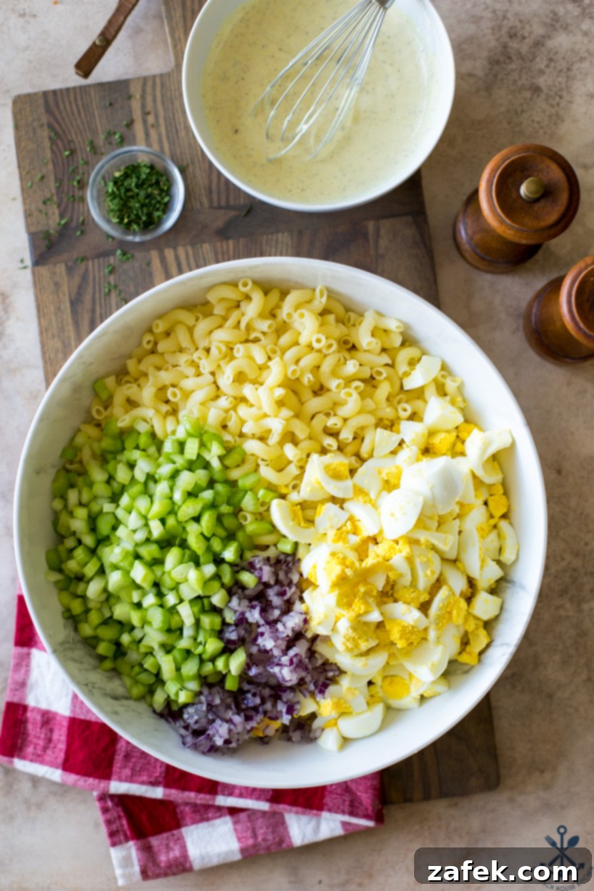Easy Macaroni Salad From Gram 3 Overhead photo of pre-mixed ingredients for macaroni salad in a white bowl, showcasing the vibrant colors of celery and red onion.