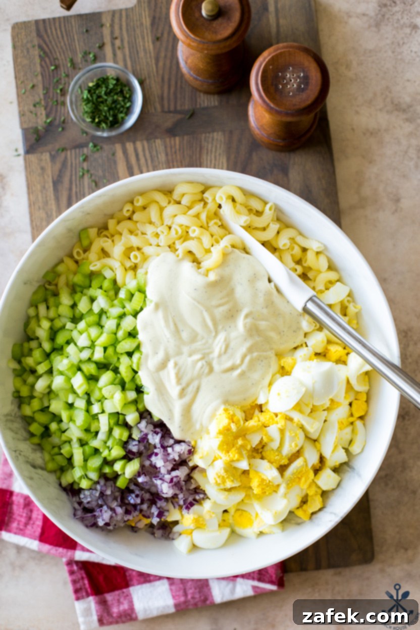 Easy Macaroni Salad From Gram 8 Overhead photo of ingredients for macaroni salad in a large bowl topped with creamy dressing, before being fully mixed.