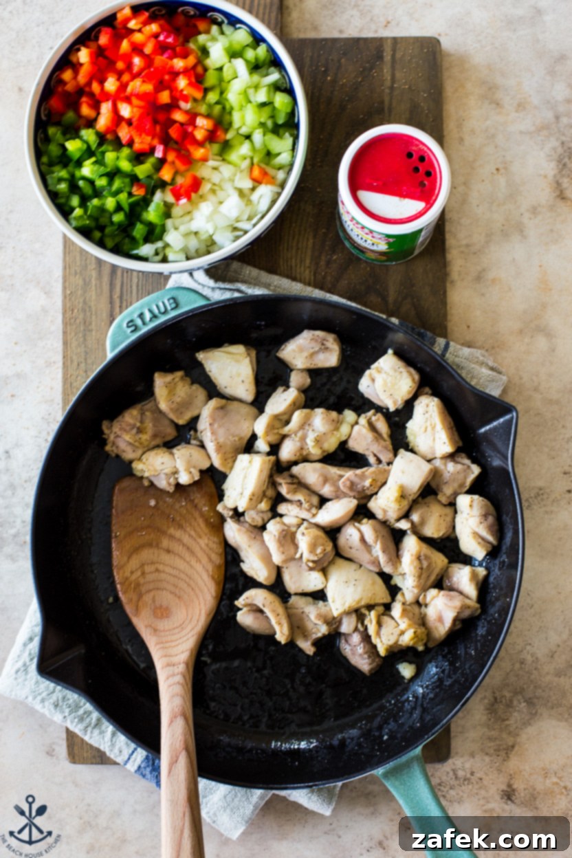 Bayou Jambalaya 5 Overhead photo of a skillet of cooked chicken with a cowl of onions, peppers and celery off to the side