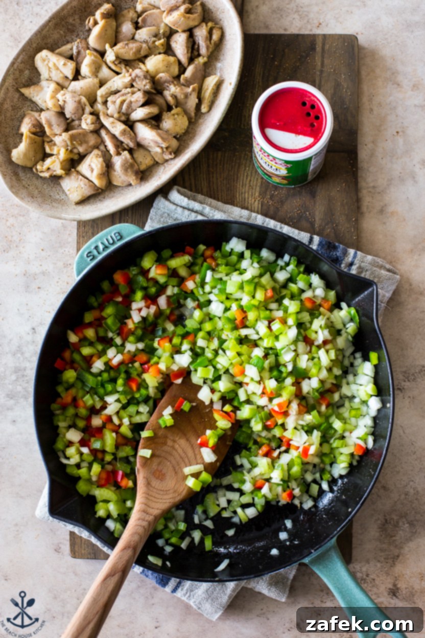 Bayou Jambalaya 6 Overhead photo of a skillet of onions, peppers and celery with a plate of cooked chicken off to the side