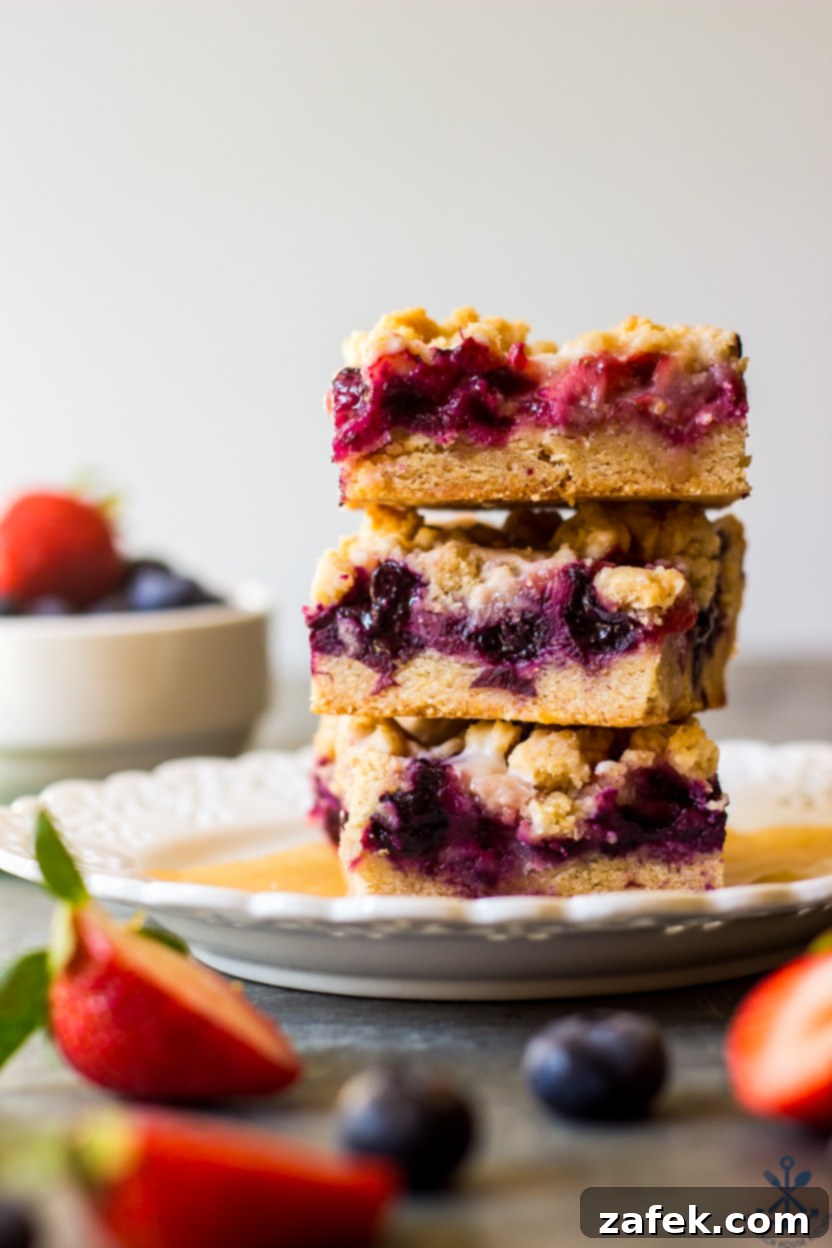 Summer Berry Streusel Bars 2 A stack of three berry crumb bars on a plate, showcasing the layers of crust, fruit, and crumb topping.
