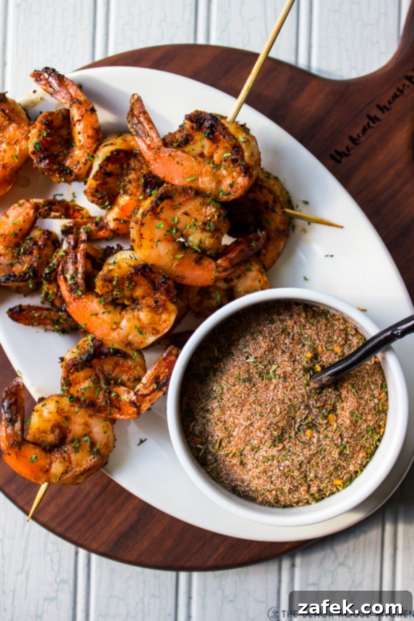 A vibrant plate of grilled shrimp skewers seasoned with Jamaican Jerk, beside a bowl of the dry rub blend.