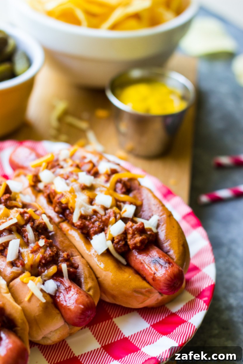 A plate of chili dogs topped with chopped onions and cheese
