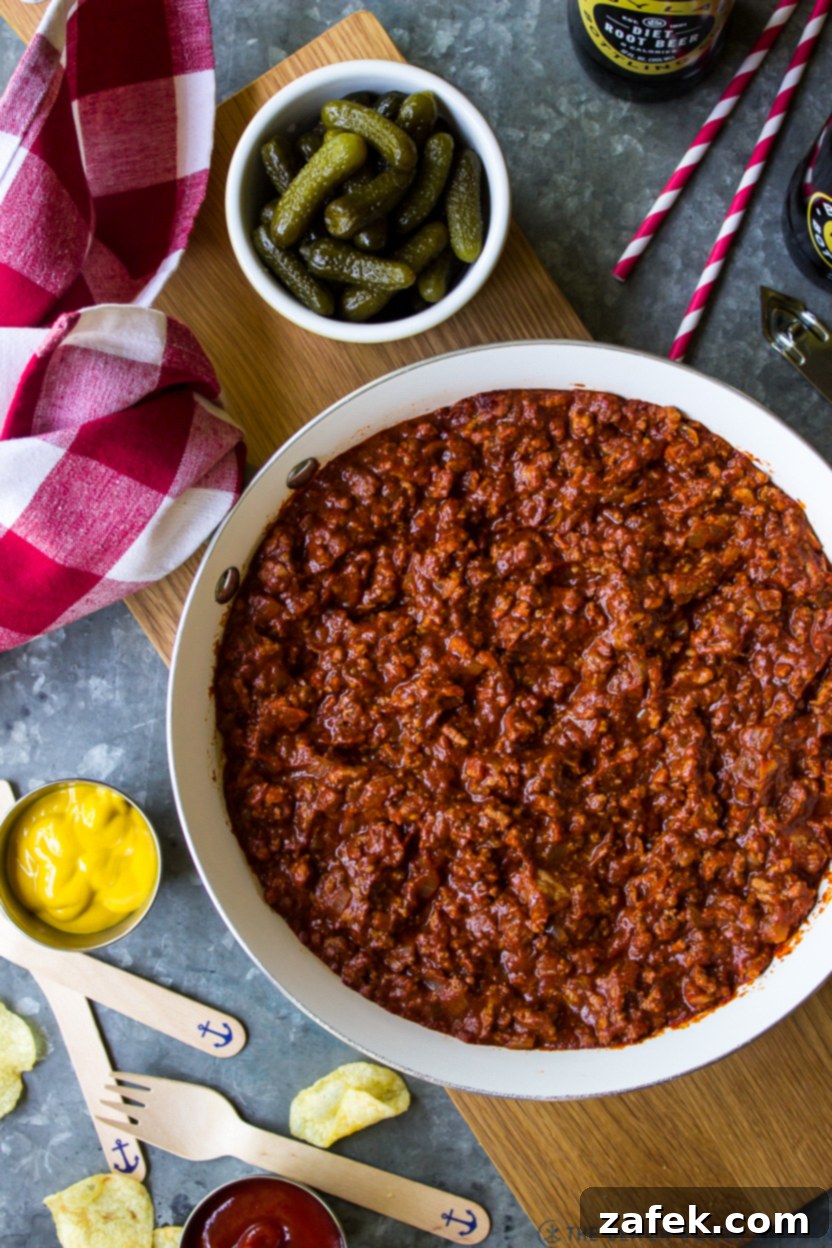 Overhead photo of a skillet of chili with a bowl of pickles off to the side
