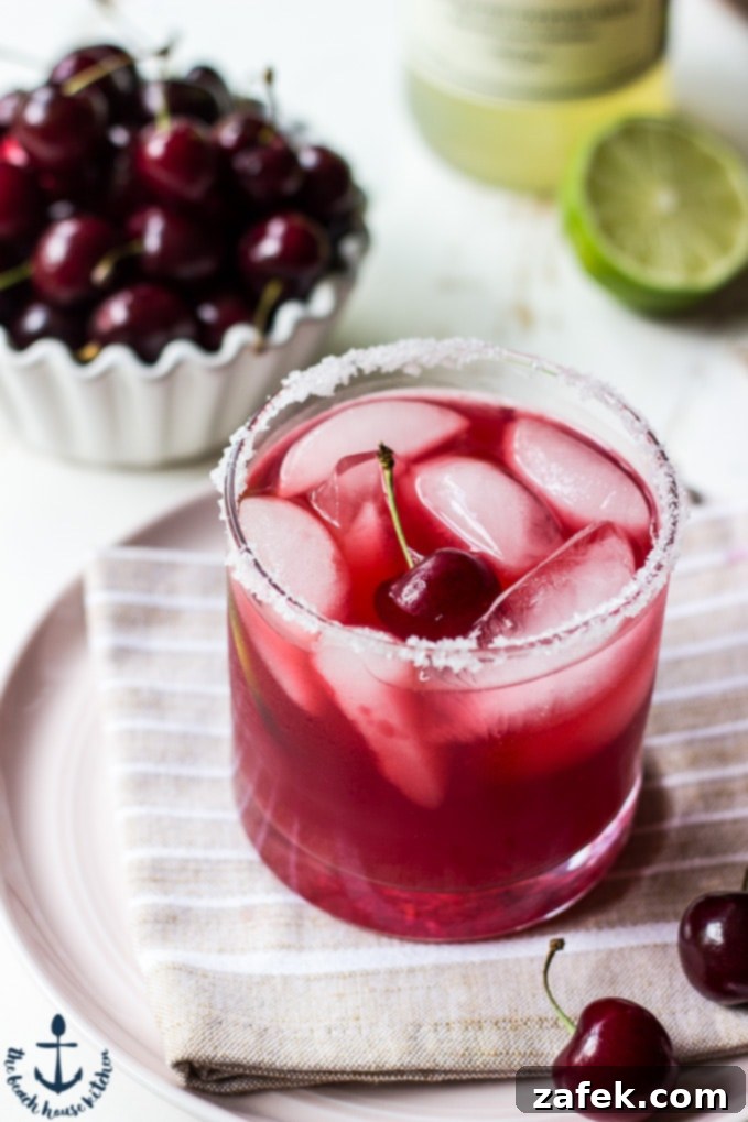 Ruby Cherry Margarita 3 Close-up of a Cherry Margarita glass with ice, cherries, and lime garnish, highlighting its refreshing appeal.