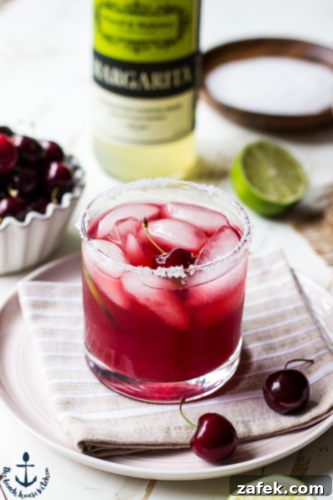 Ruby Cherry Margarita 5 A vibrant Cherry Margarita garnished with a fresh cherry and a lime slice on a rustic surface.