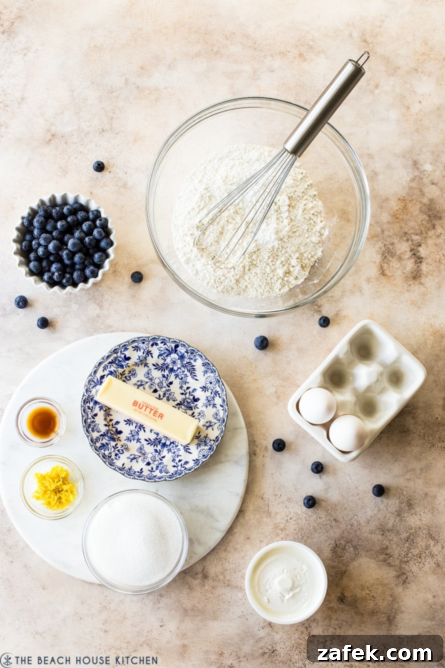 Blueberry Lemon Loaf 4 Overhead photo of ingredients for Blueberry Lemon Loaf in bowls of different sizes on a tan background