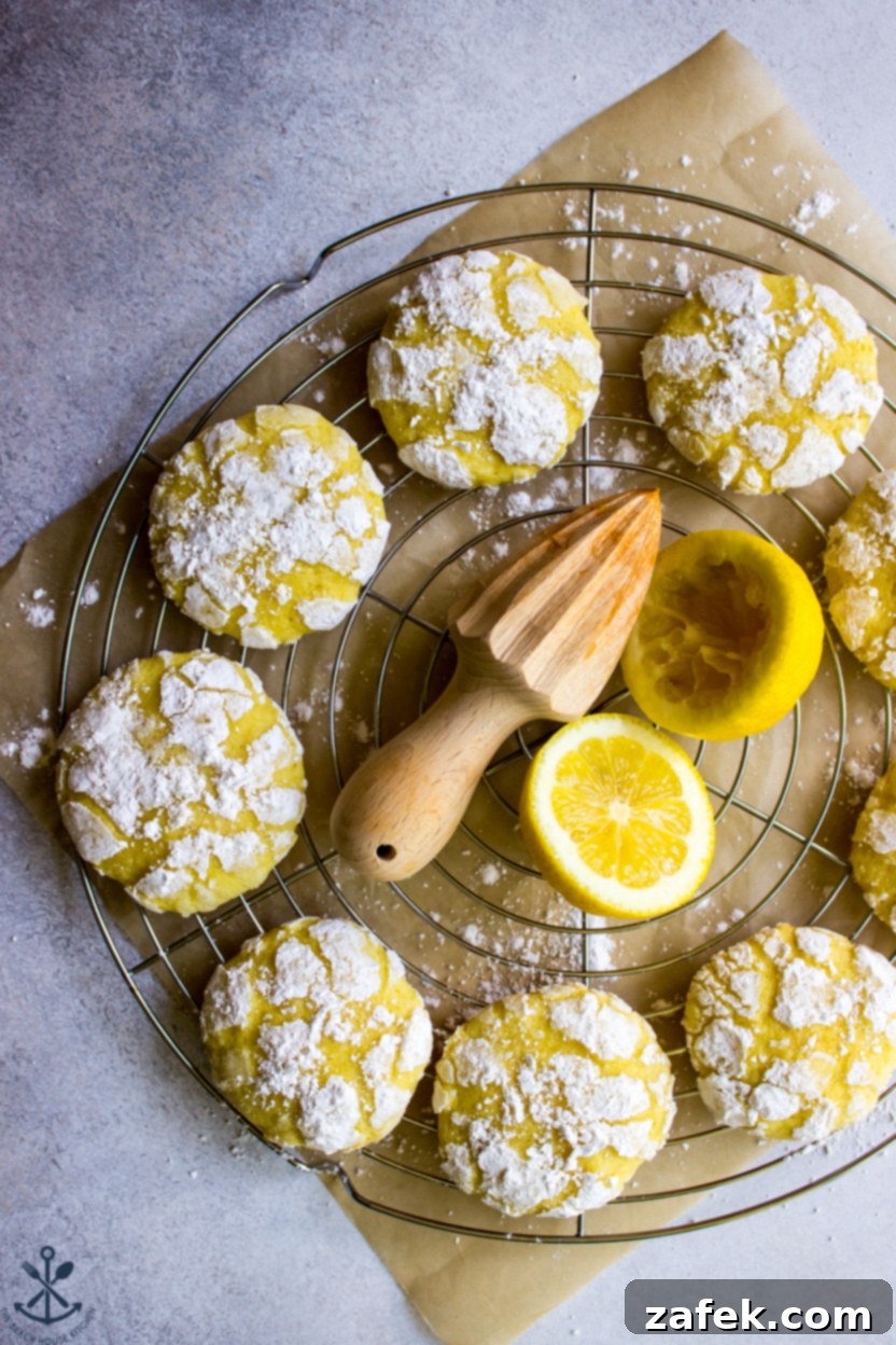 Overhead photo of golden yellow lemon crinkle cookies dusted with powdered sugar on a round wire rack