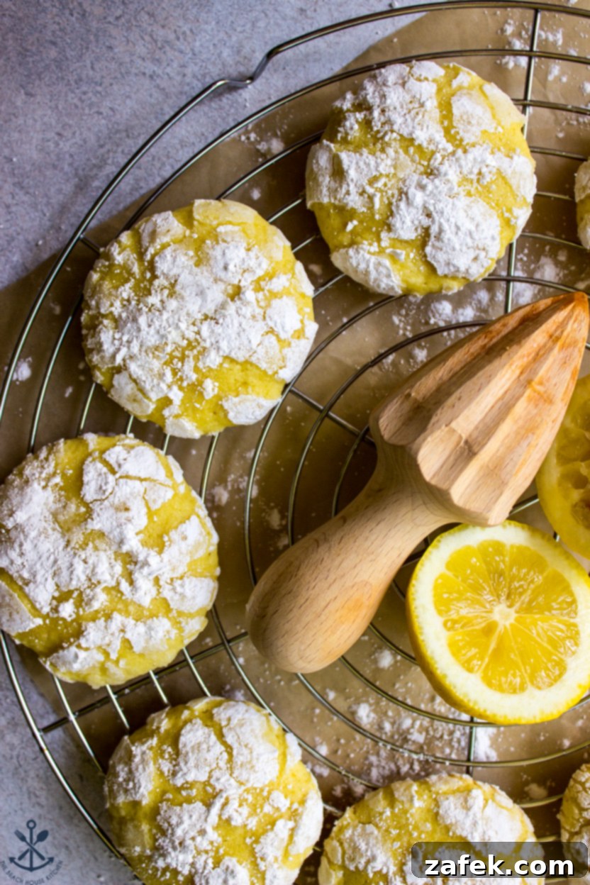 Up close photo of several lemon crinkle cookies on a silver round wire rack, highlighting their powdered sugar coating and texture