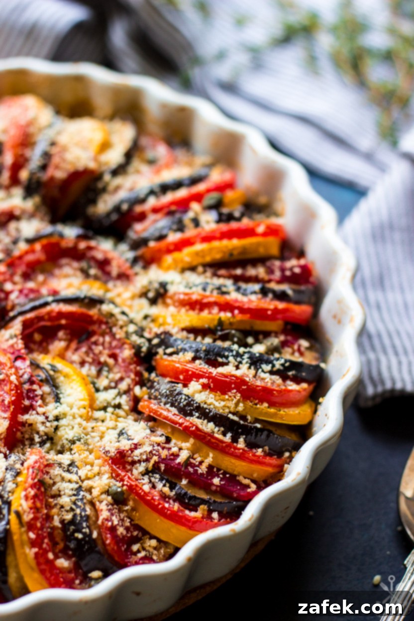 A close-up of a serving of Provençal Vegetable Tian on a plate, showcasing the beautiful layers and golden crust