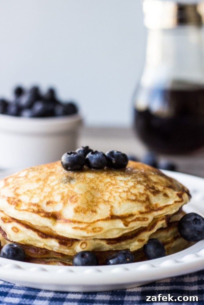 Fluffy Buttermilk Blueberry Stacks 5 A close-up shot of a single perfectly cooked buttermilk blueberry pancake, golden brown with visible blueberries, ready for syrup.