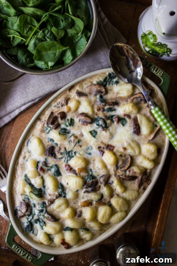 A close-up view of the creamy Mushroom Florentine Gnocchi in an oval baking dish, showcasing the tender gnocchi, sliced mushrooms, and visible spinach leaves, ready to be served.