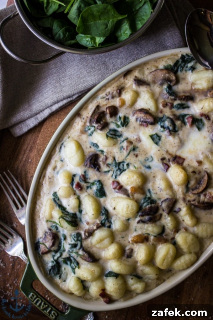 A wide shot of the baked Mushroom Florentine Gnocchi, golden and bubbling, served in an elegant oval dish on a rustic wooden tray, highlighting its autumnal appeal.