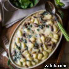 Mushroom Florentine Gnocchi in a serving dish, ready to eat, on a wooden surface.
