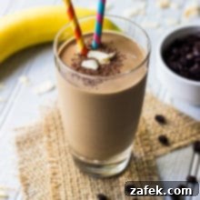 Coconut Mocha Boost Smoothie 2 Chocolate Coconut Coffee Smoothie with two colorful straws, on top of two pieces of burlap ribbon with a banana in background.