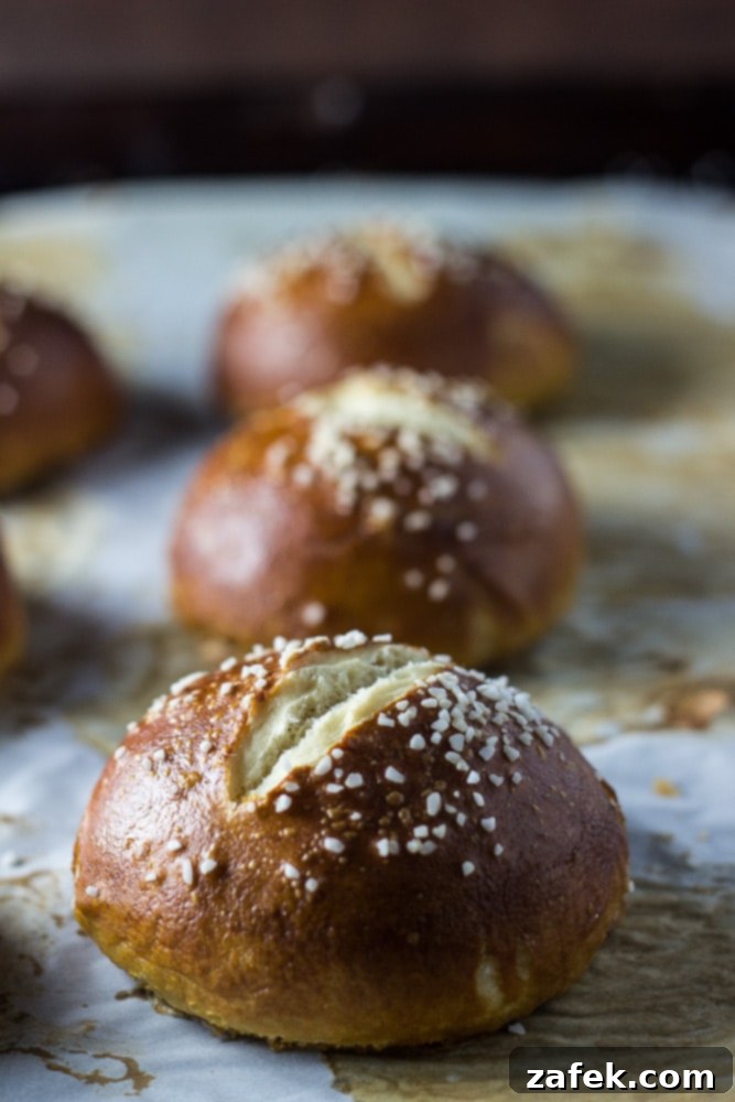 Soft Pretzel Buns 3 Close-up shot of freshly baked pretzel rolls cooling on a wire rack, highlighting their unique texture and golden-brown sheen.