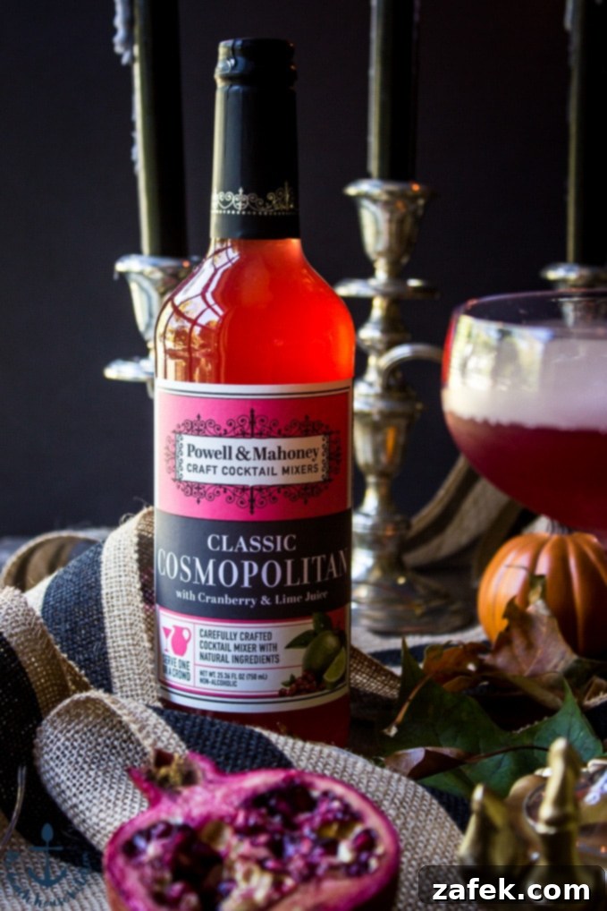 Vampires-Venom-Cocktail Red bottle of cocktail mixer with pomegranate, striped burlap ribbon and candles in the background.