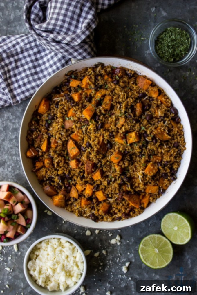 Skillet of Chipotle Sweet Potato Quinoa Taco Filling A vibrant skillet filled with chipotle sweet potato and quinoa mix, surrounded by bowls of shredded cheese, fresh salsa, chopped cilantro, and sliced limes, ready for taco assembly.