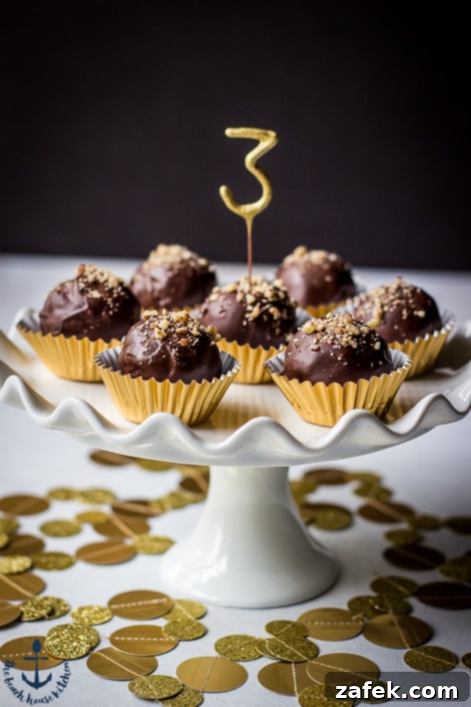 Close-up of delicious Pecan Pie Truffles in gold foil cups on a white cake pedestal, adorned with a number 3 pick in the center truffle.