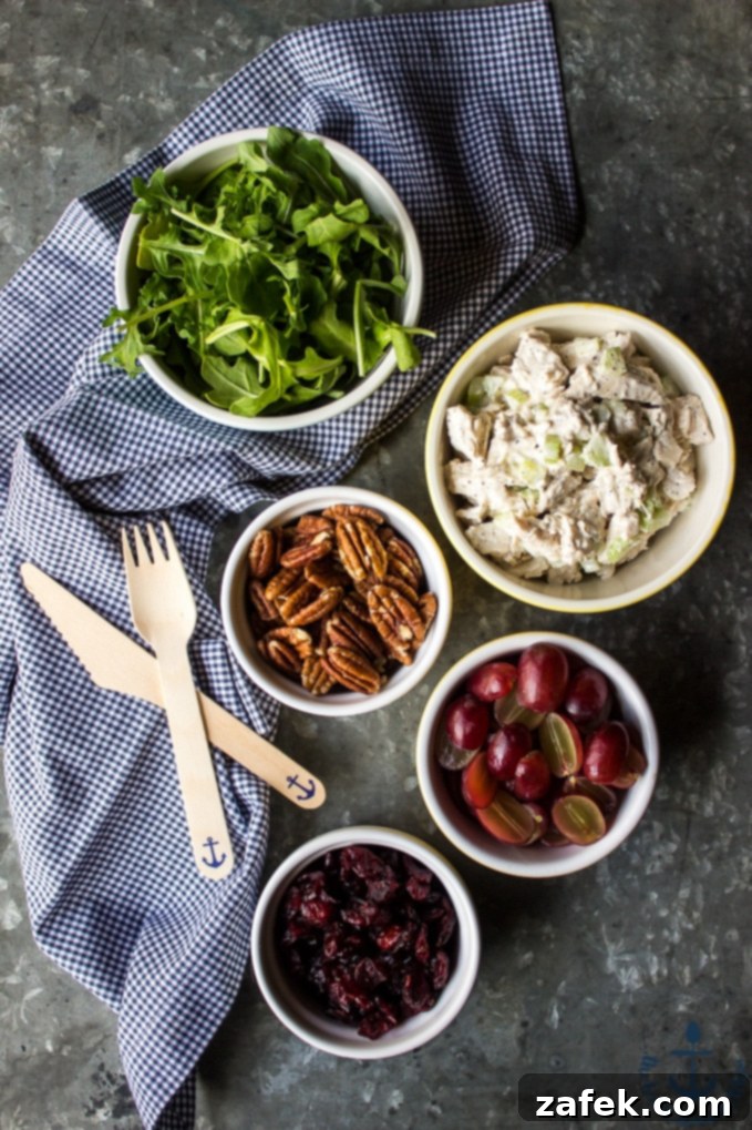 All the fresh ingredients laid out for Turkey Salad with Grapes, Pecans and Cranberries in a Jar, including cooked turkey, grapes, pecans, cranberries, celery, onion, and fresh tarragon.