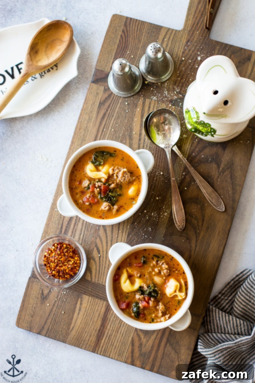 Overhead photo of white bowls on a wooden board filled with delicious tomato tortellini stew, garnished with fresh herbs.