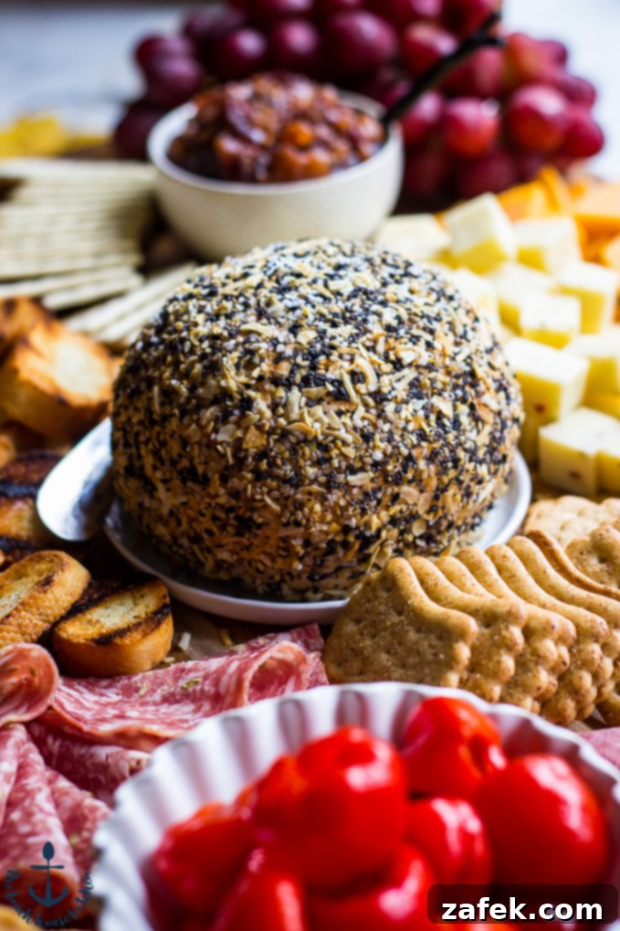 Epic Fall Cheese Board - Everything Cheddar Horseradish Cheese Ball Vibrant Everything Cheddar Horseradish Cheese Ball surrounded by an assortment of crackers, savory salami slices, colorful peppers, and juicy red grapes, perfect for a festive gathering.