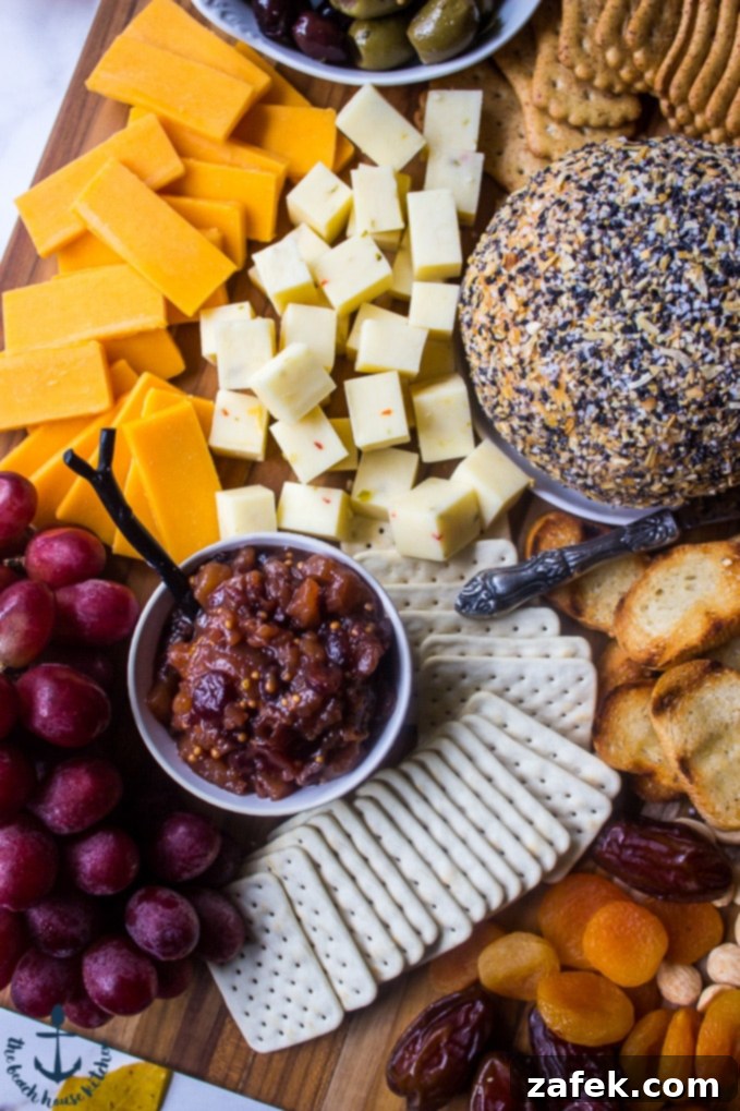 Epic Fall Cheese Board - Everything Cheddar Horseradish Cheese Ball Overhead perspective of a beautifully arranged cheese board featuring various cheeses, an elegant chutney in a white bowl, fresh grapes, and the prominent Everything Cheddar Horseradish Cheese Ball.