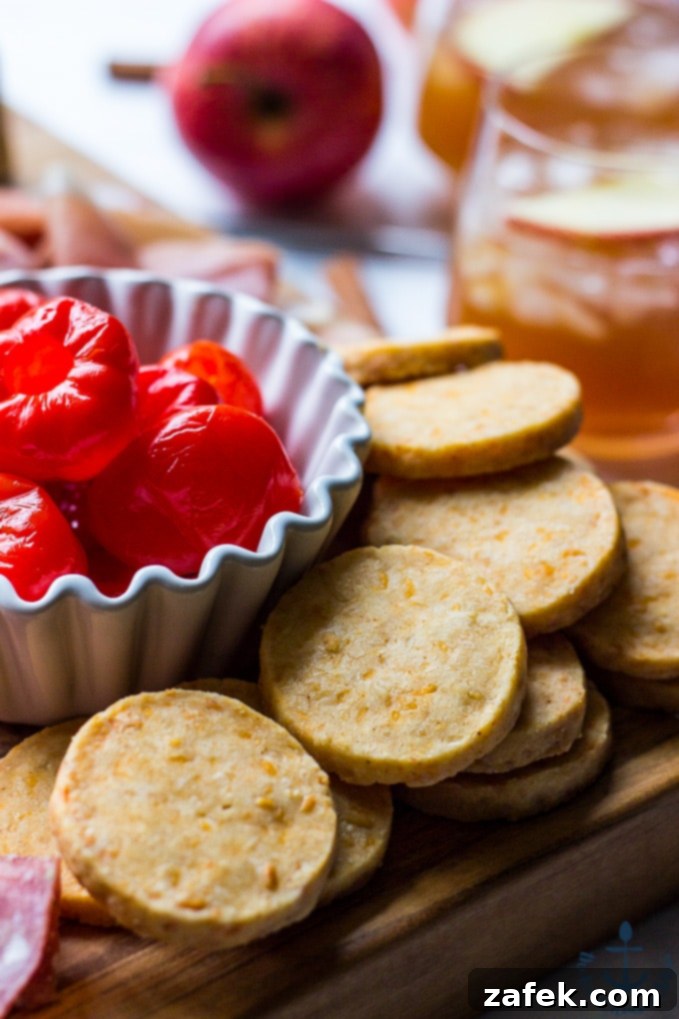 Epic Fall Cheese Board - Everything Cheddar Horseradish Cheese Ball Close-up photograph featuring golden cheddar cheese coins and bright red peppadew peppers, adding color and flavor to the cheese board arrangement.