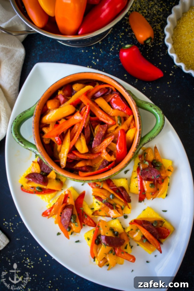 Sweet Pepper and Chorizo Bruschetta Polenta Bites on a white oval platter with a green bowl filled with red and yellow pepper strips.