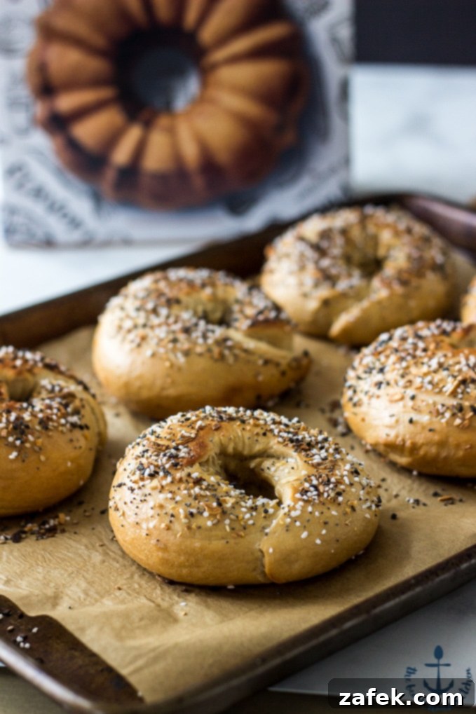 Homemade Bagel Success Freshly baked Everything Bagels on a parchment-lined baking sheet, with the Zingerman's cookbook open in the background.