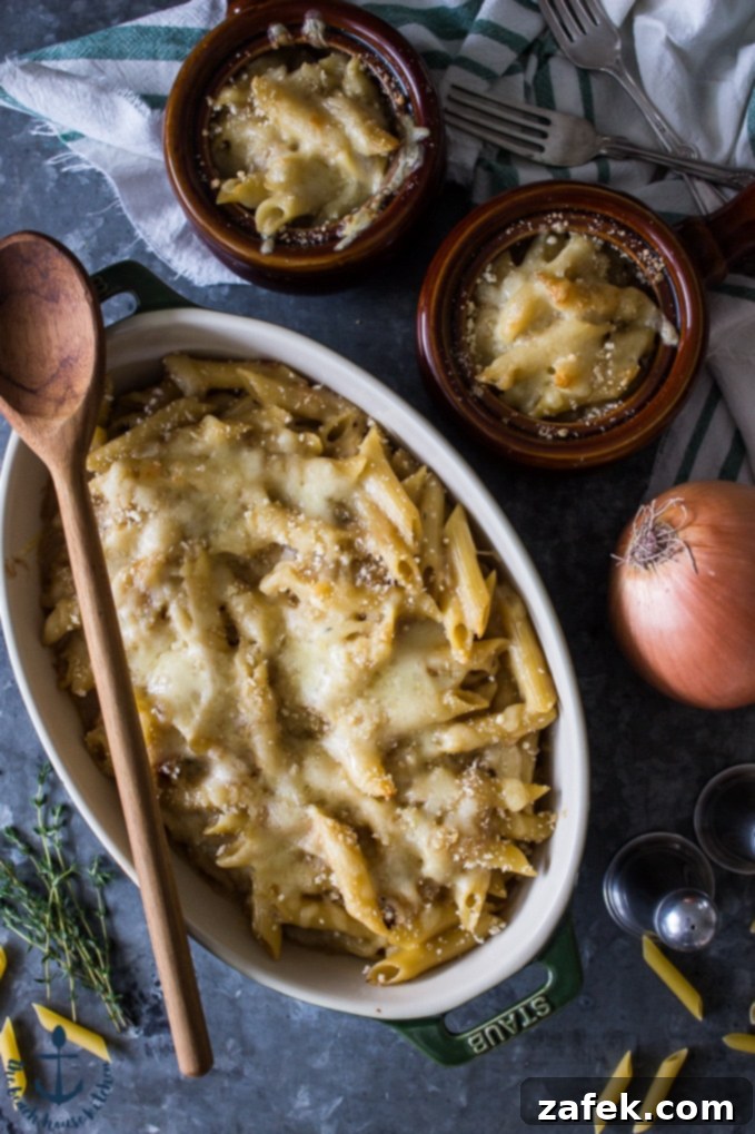 French Onion Pasta Bake - Comfort Food Overhead shot of a beautifully golden-brown French onion pasta bake, generously topped with melted Swiss cheese and golden panko crumbs, resting in a large ceramic baking dish. Two smaller individual portions are visible on the side, inviting a closer look at the rich pasta and caramelized onions within.