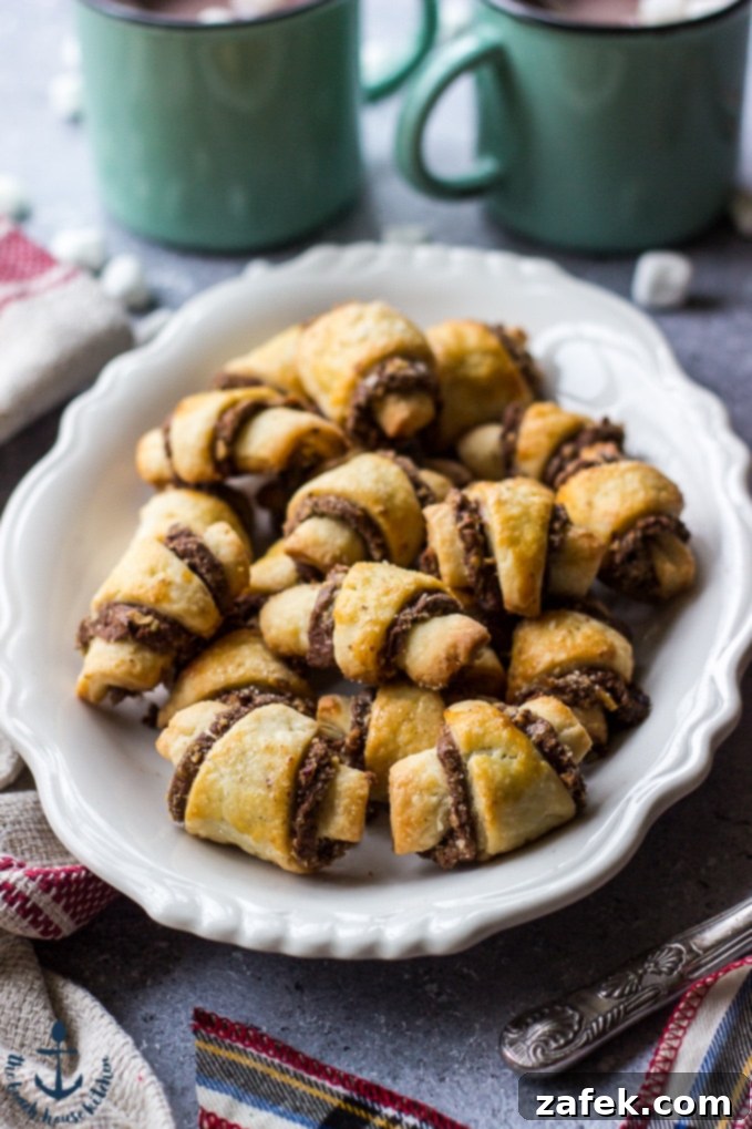 Nutella-Pecan-Rugelach Nutella Pecan Rugelach on white platter with cups of cocoa, and plaid ribbon.