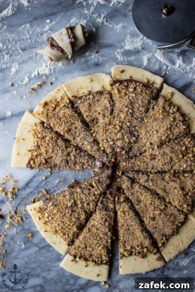 Nutella-Pecan-Rugelach Overhead shot of nutella pecan rugelach on marble board cut into wedges before rolling.
