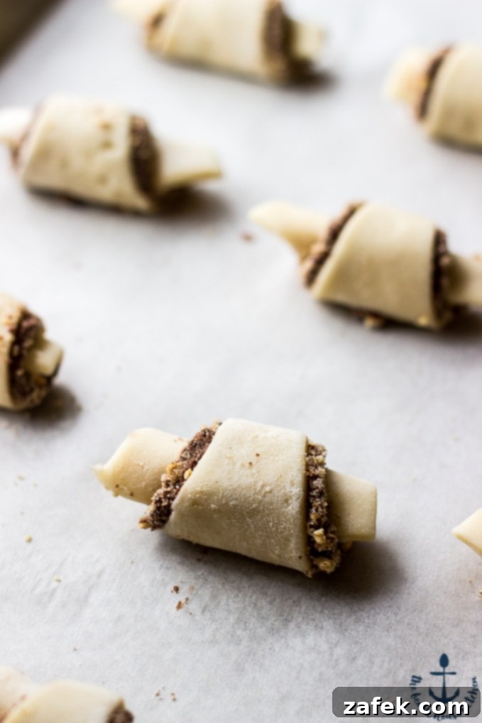 Nutella-Pecan-Rugelach Rolled Nutella Pecan Rugelach on parchment lined baking sheet before baking.